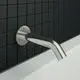Wandauslauf aus Edelstahl von Ideal Standard, montiert an einer dunklen Fliesenwand, mit einem geraden Auslauf auf eine weiße Badewanne.